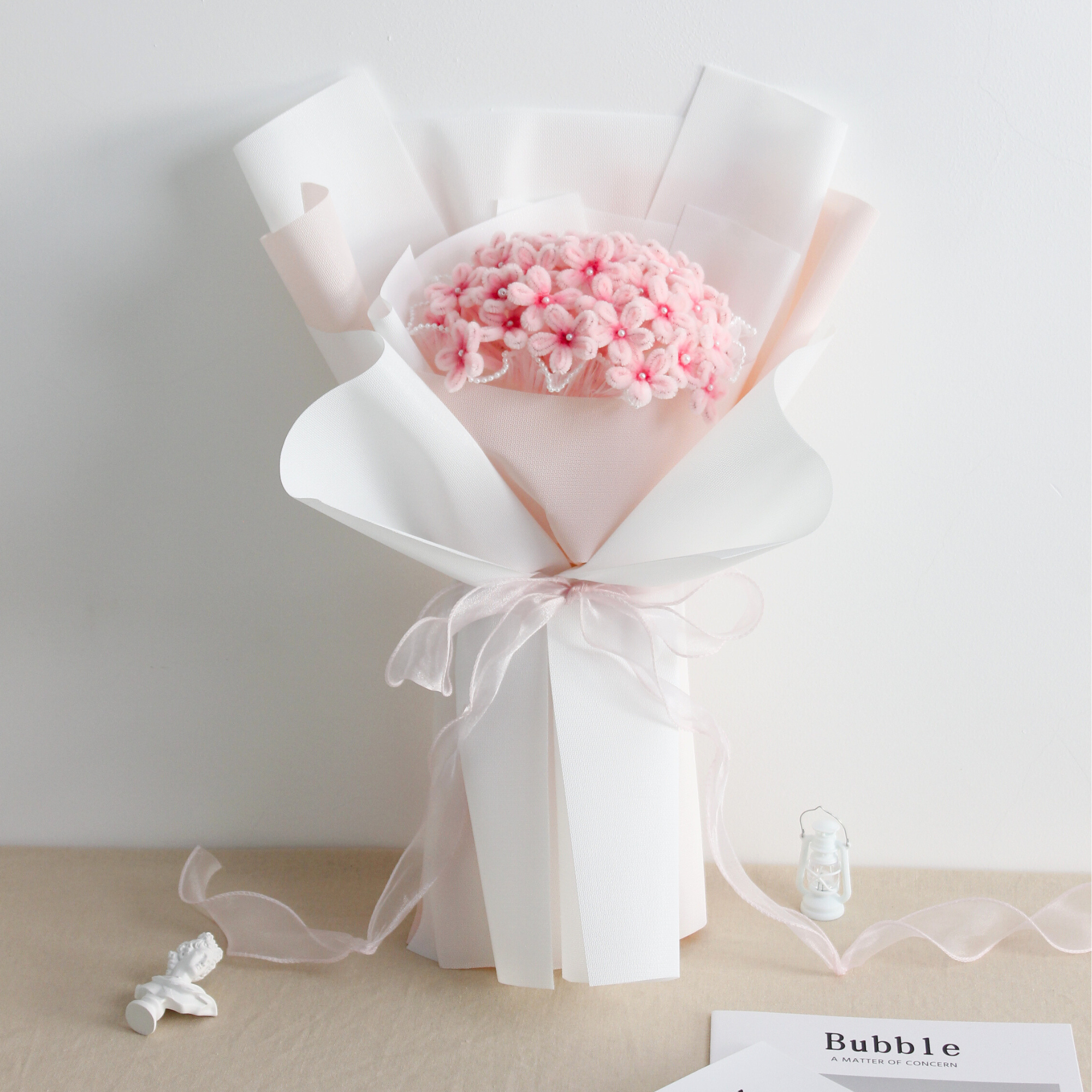 DIY bouquet of delicate pink hydrangea flowers, handmade from soft pipe cleaners with tiny pearl-like centers. Wrapped in soft pink and white paper with a sheer ribbon a dreamy handmade gift.