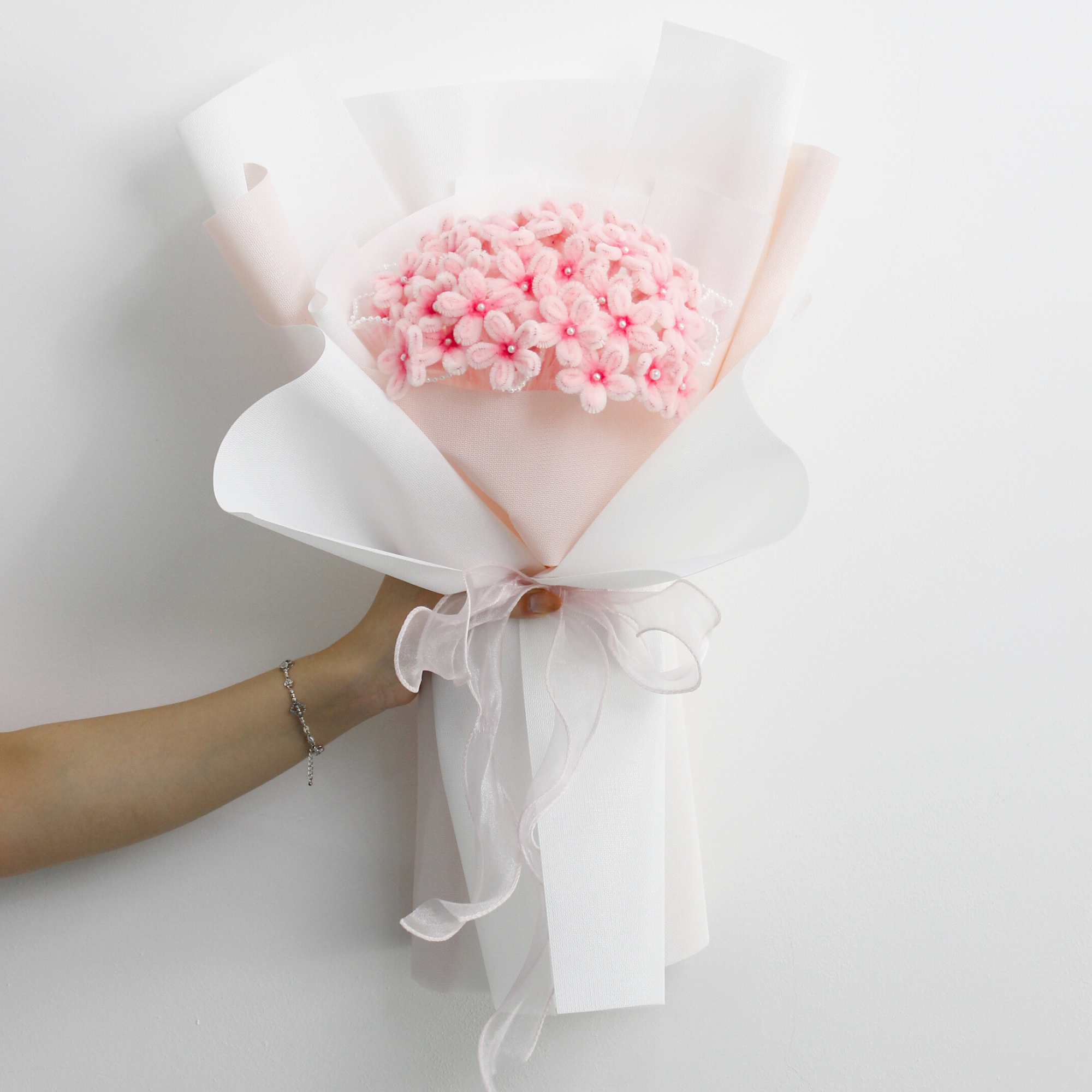 DIY bouquet of delicate pink hydrangea flowers, handmade from soft pipe cleaners with tiny pearl-like centers. Wrapped in soft pink and white paper with a sheer ribbon a dreamy handmade gift.