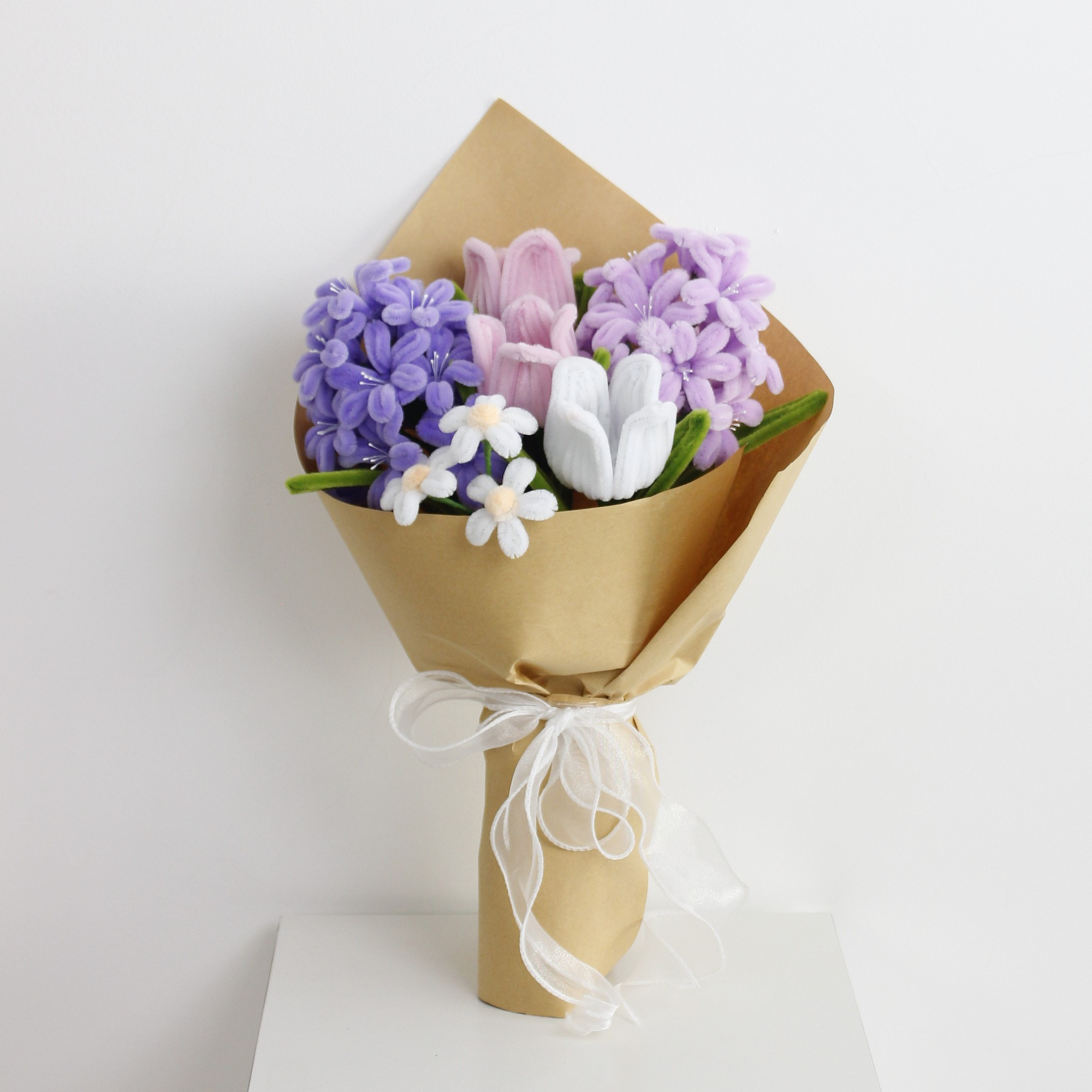 Violet Grace DIY bouquet featuring handcrafted lilac and purple hyacinths, pink and white tulips, and dainty white blossoms made from pipe cleaners. Wrapped in kraft paper with a soft white ribbon, perfect for elegant handmade gifts.