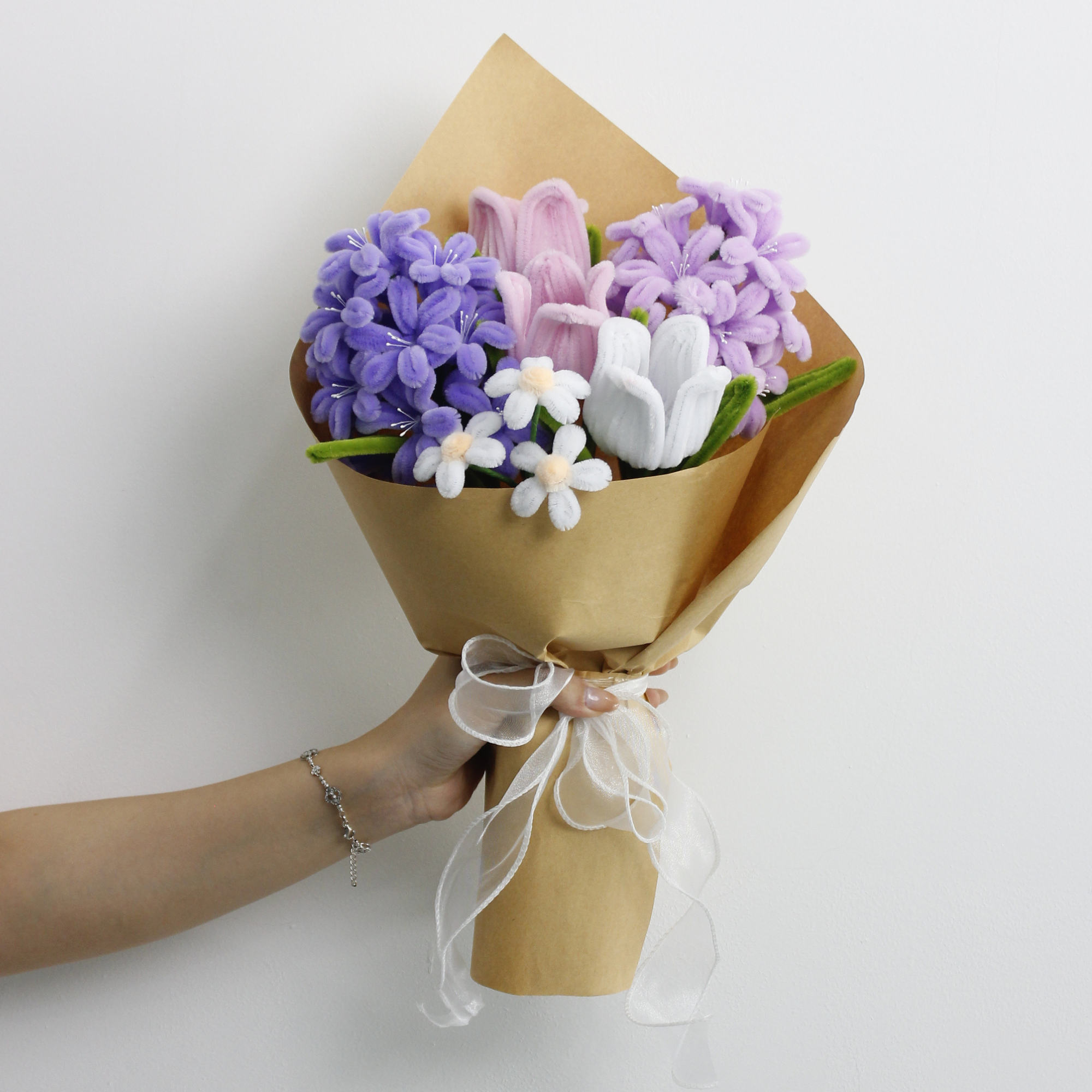 Violet Grace DIY bouquet featuring handcrafted lilac and purple hyacinths, pink and white tulips, and dainty white blossoms made from pipe cleaners. Wrapped in kraft paper with a soft white ribbon, perfect for elegant handmade gifts.