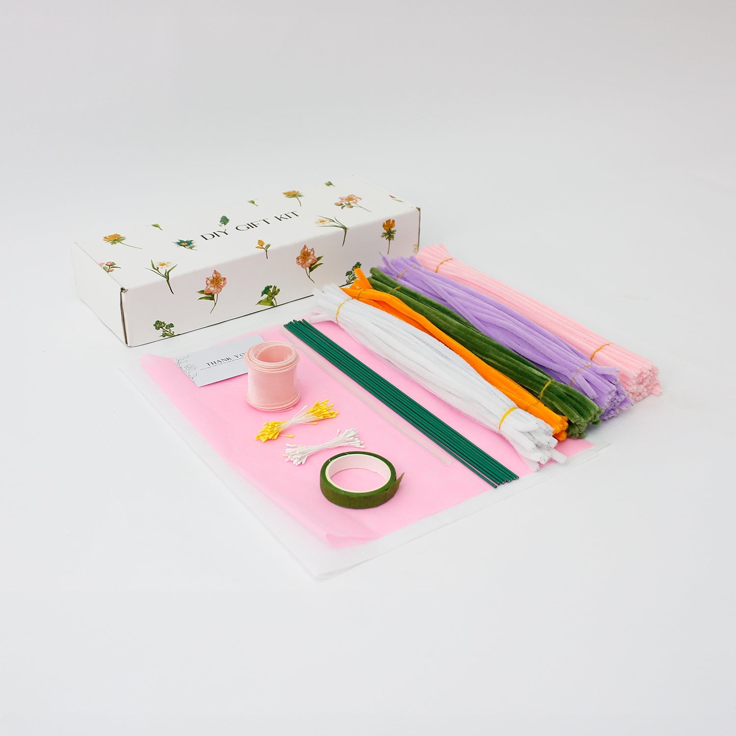 Lily Whisper DIY bouquet made from soft pipe cleaners, featuring pastel lilies, tulips, and a blooming purple carnation. Wrapped in sheer white and pink layers with a soft organza bow a handmade floral gift full of grace.