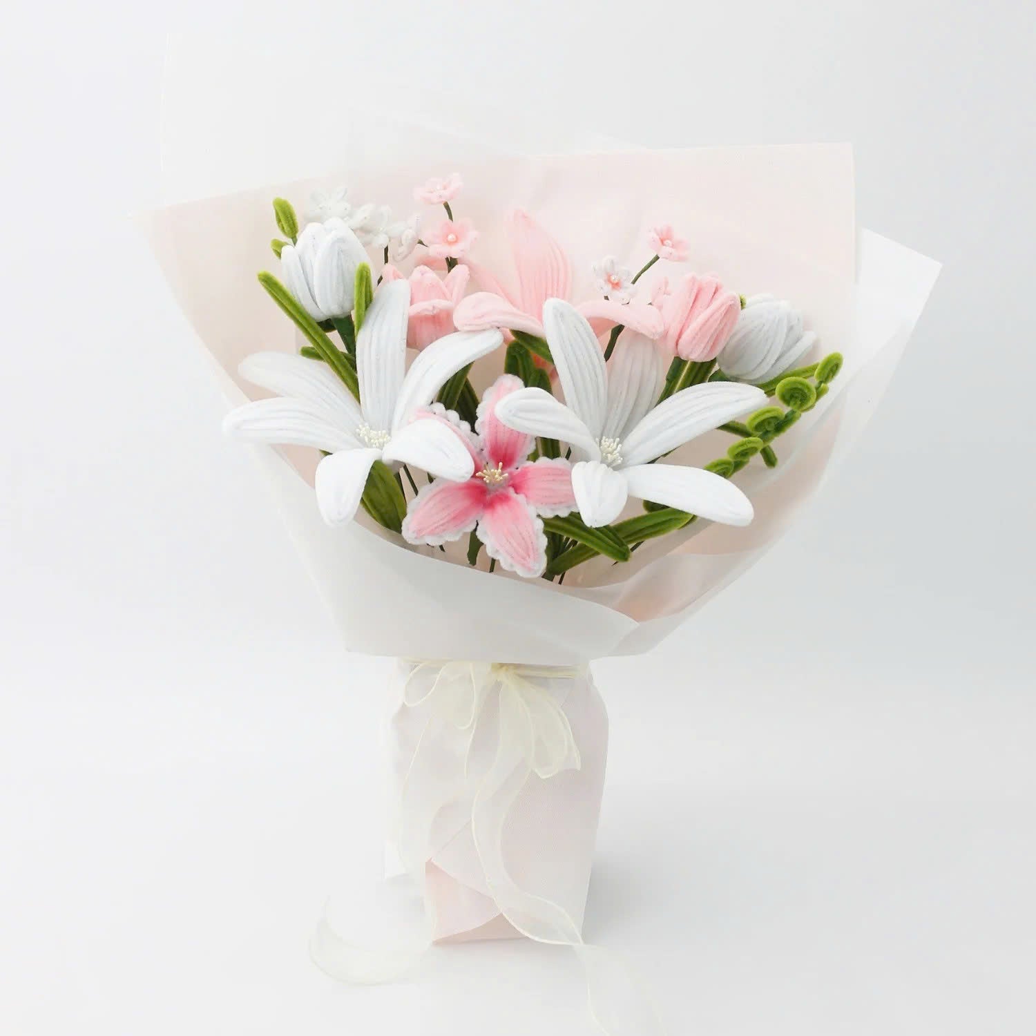Pastel Bloom DIY bouquet crafted from pipe cleaners, featuring soft white and blush pink lilies, tulips, and delicate filler flowers. Wrapped in sheer pastel wrapping with a flowing organza ribbon an elegant, handmade floral craft kit for gifting or display.