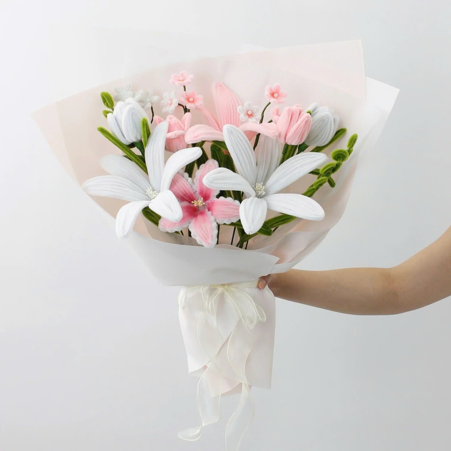 Pastel Bloom DIY bouquet crafted from pipe cleaners, featuring soft white and blush pink lilies, tulips, and delicate filler flowers. Wrapped in sheer pastel wrapping with a flowing organza ribbon an elegant, handmade floral craft kit for gifting or display.
