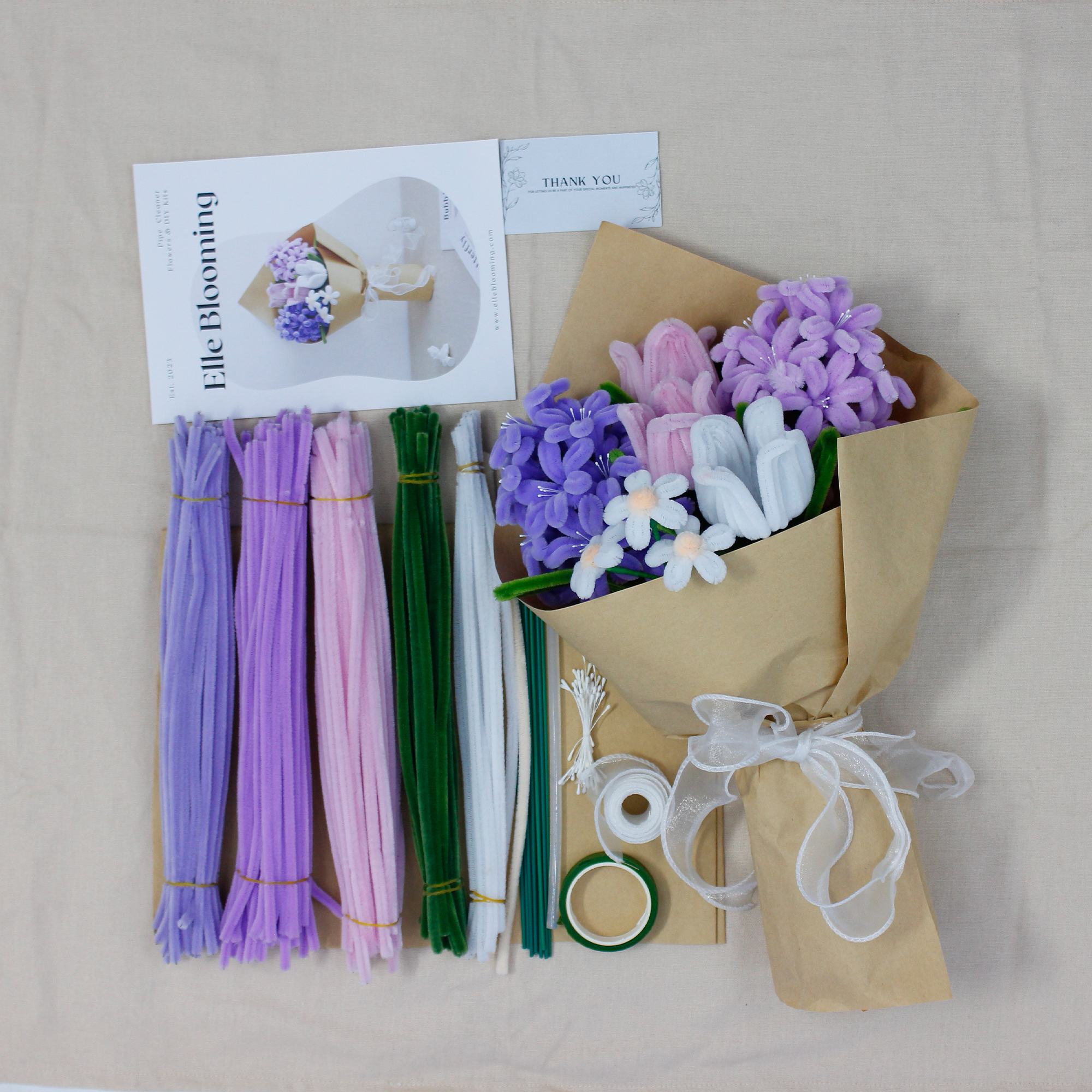 Elegant DIY kit featuring a bouquet of violet, pink, and white pipe cleaner flowers, complete with crafting materials and gift-ready packaging.
